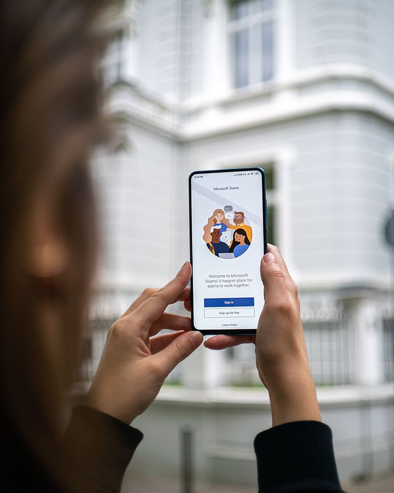 A person holding a smartphone in front of an office building